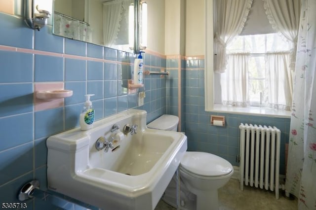 bathroom with toilet, radiator, tile walls, and sink