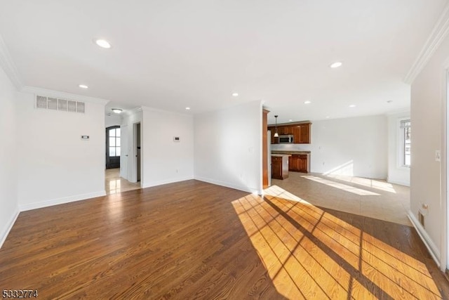 unfurnished living room featuring a wealth of natural light, dark hardwood / wood-style flooring, and ornamental molding