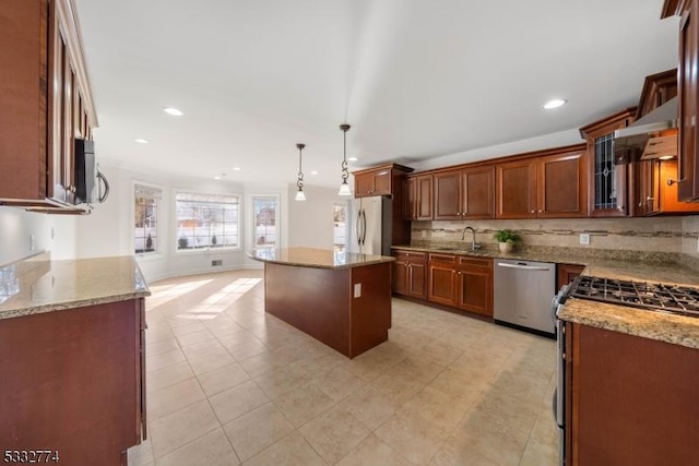 kitchen with a kitchen island, decorative light fixtures, stainless steel appliances, sink, and light stone counters