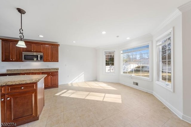 kitchen with hanging light fixtures, light stone countertops, a wealth of natural light, and ornamental molding