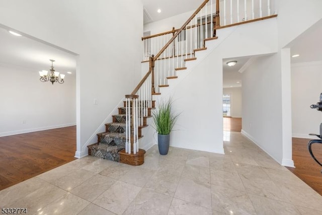 stairway with a notable chandelier, crown molding, and a towering ceiling