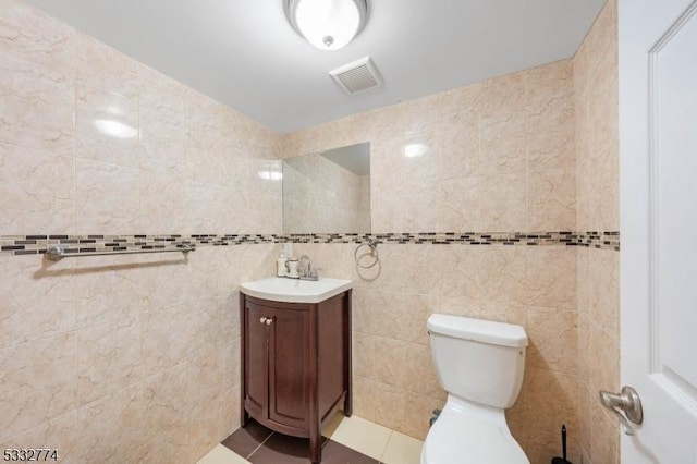 bathroom with toilet, tile walls, tile patterned floors, and vanity