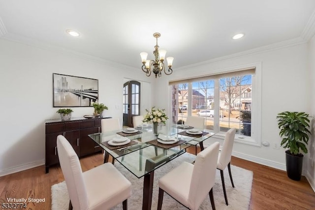 dining space featuring light hardwood / wood-style floors, ornamental molding, and a notable chandelier