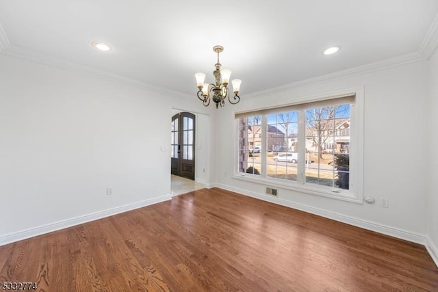 unfurnished dining area featuring hardwood / wood-style floors, crown molding, french doors, and an inviting chandelier