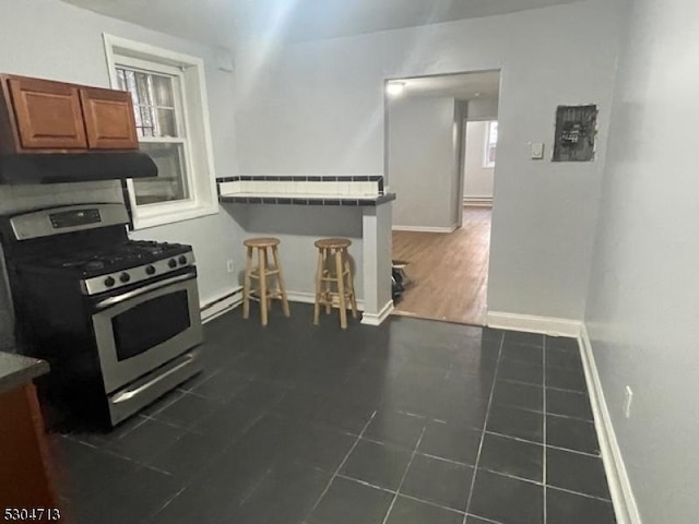 kitchen featuring gas range, ventilation hood, and dark tile patterned flooring