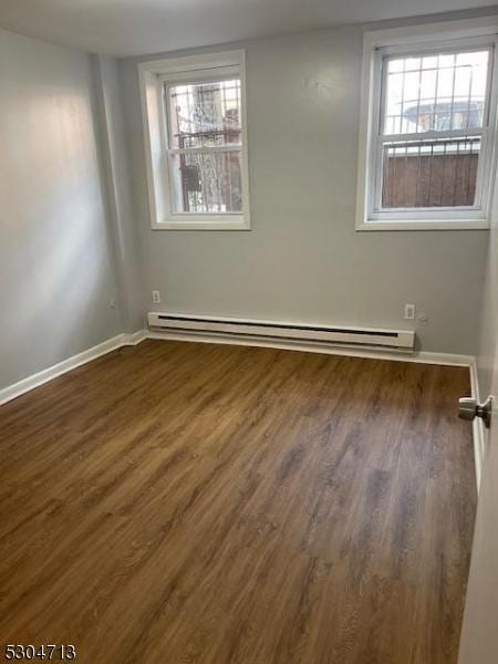 spare room with dark hardwood / wood-style floors and a baseboard radiator