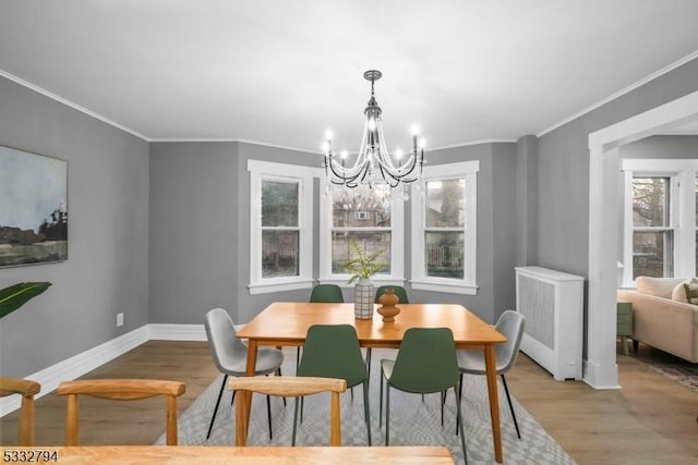 dining area featuring radiator, ornamental molding, light hardwood / wood-style floors, and a notable chandelier