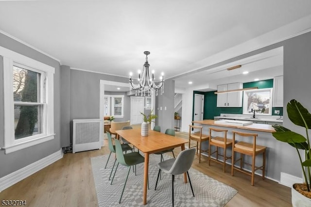 dining space with an inviting chandelier, crown molding, light hardwood / wood-style flooring, and sink