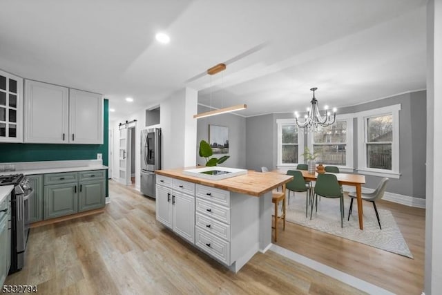 kitchen with a barn door, light hardwood / wood-style floors, white cabinetry, stainless steel appliances, and wood counters