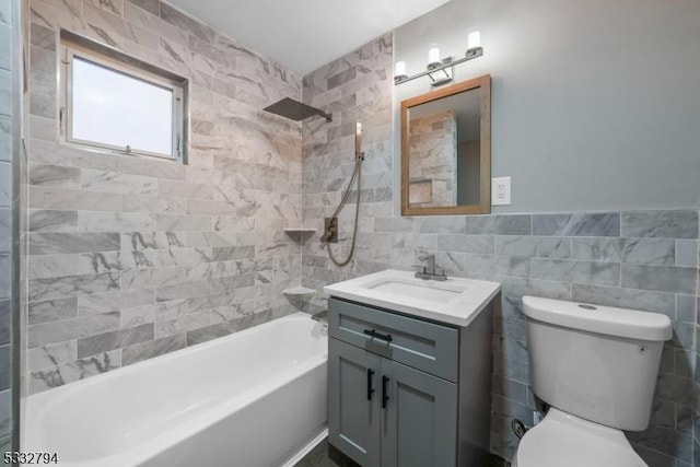 full bathroom featuring toilet, tiled shower / bath combo, tile walls, and vanity