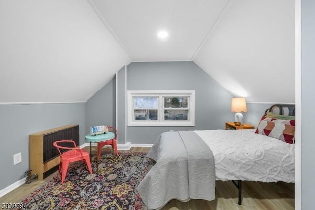 bedroom featuring heating unit, vaulted ceiling, and hardwood / wood-style floors