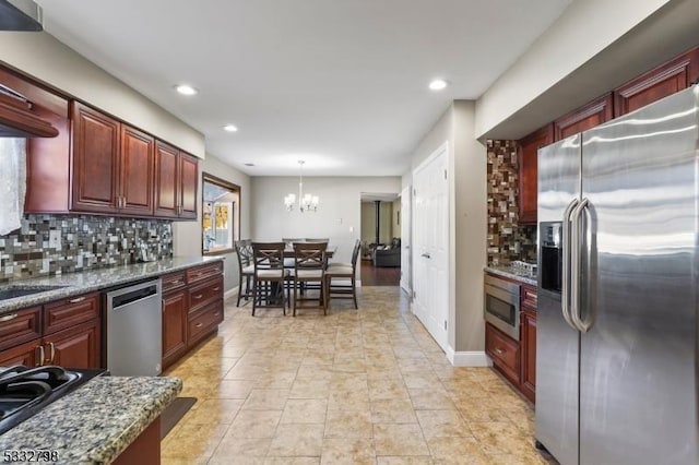 kitchen featuring pendant lighting, a notable chandelier, tasteful backsplash, dark stone counters, and appliances with stainless steel finishes