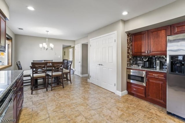 kitchen with decorative light fixtures, decorative backsplash, dark stone counters, a chandelier, and appliances with stainless steel finishes