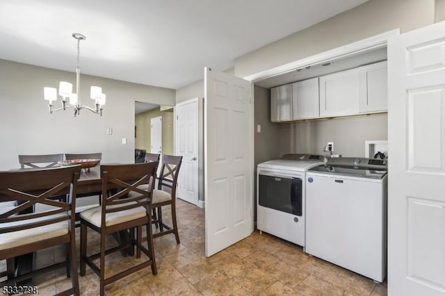 clothes washing area with washing machine and dryer, cabinets, and a notable chandelier