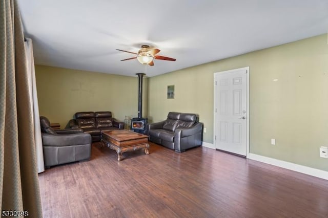 living room with ceiling fan, dark wood-type flooring, and a wood stove