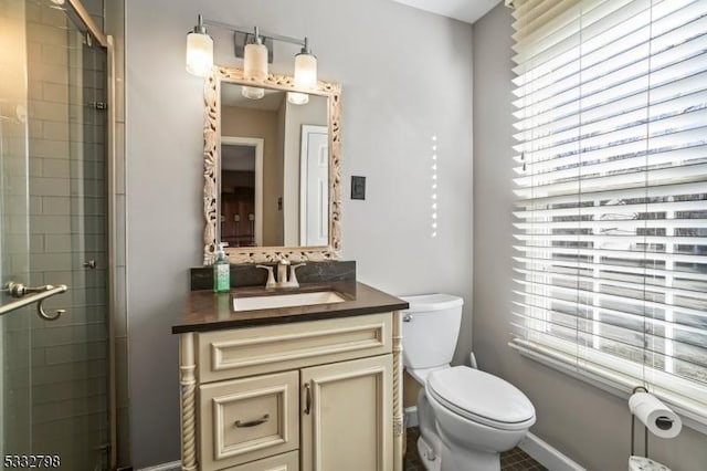 bathroom featuring toilet, vanity, a healthy amount of sunlight, and walk in shower