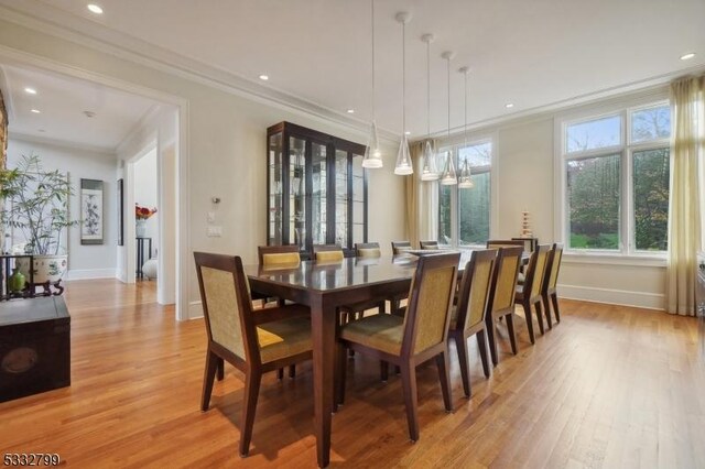 dining space with a notable chandelier, light hardwood / wood-style floors, and crown molding