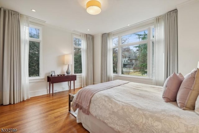 bedroom with hardwood / wood-style flooring, crown molding, and multiple windows