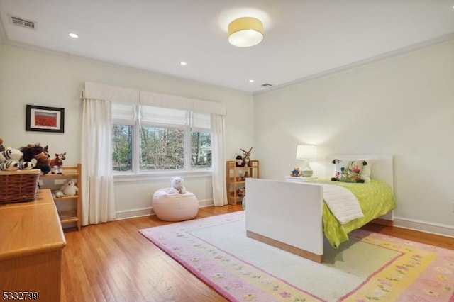 bedroom featuring ornamental molding and light hardwood / wood-style flooring