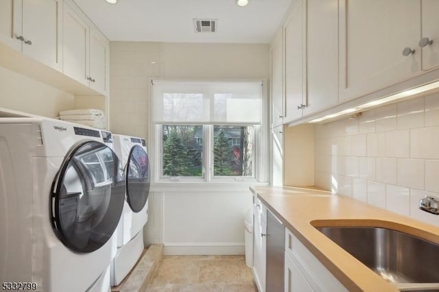 laundry area featuring separate washer and dryer, cabinets, and sink