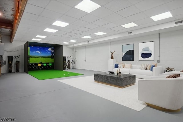 living room featuring golf simulator, a drop ceiling, and concrete floors