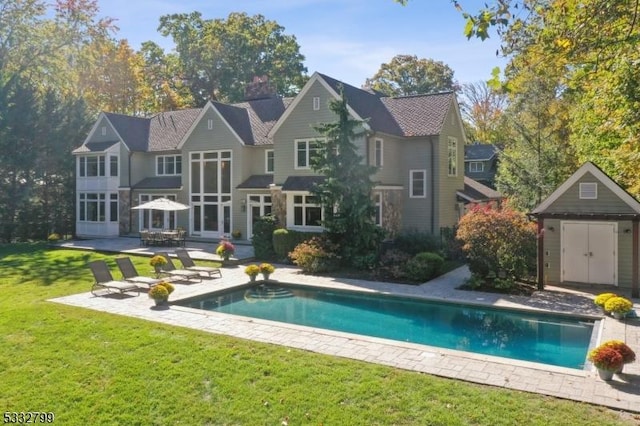 back of property with a fire pit, a yard, a storage unit, and a patio area