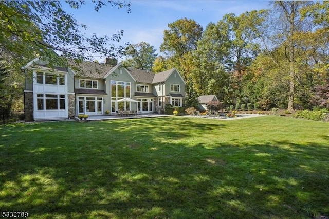 back of property featuring a lawn, a patio area, and a sunroom