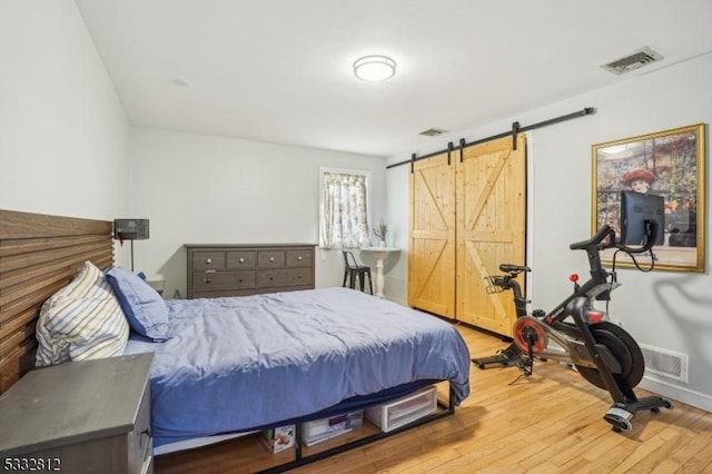 bedroom with hardwood / wood-style flooring and a barn door