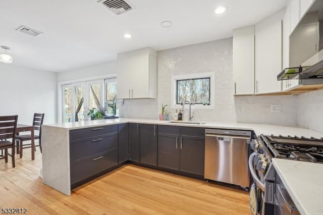 kitchen featuring stainless steel appliances, sink, white cabinetry, light stone counters, and light hardwood / wood-style floors