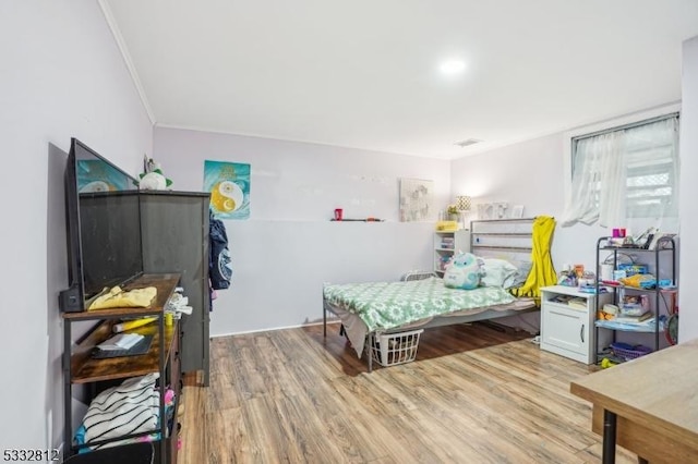 bedroom featuring crown molding and light hardwood / wood-style flooring