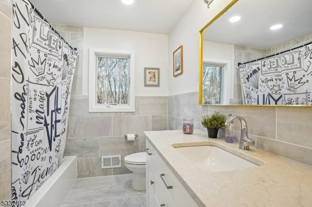 full bathroom with toilet, tile walls, shower / tub combo with curtain, and vanity