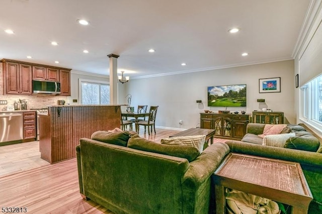 living room featuring ornamental molding, a wealth of natural light, a notable chandelier, and light hardwood / wood-style flooring