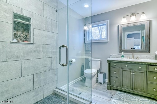 bathroom with toilet, vanity, and a shower with shower door