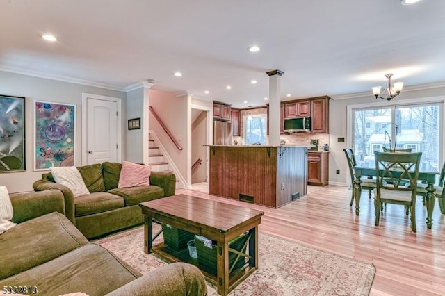 living room featuring a notable chandelier, light wood-type flooring, and ornamental molding