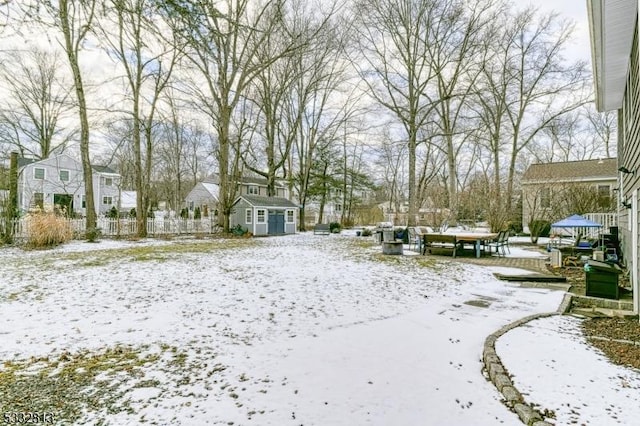 yard layered in snow featuring a shed