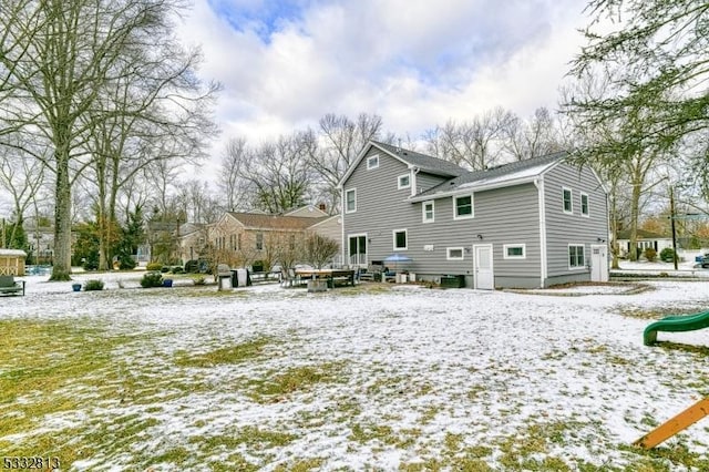 snow covered house featuring a playground