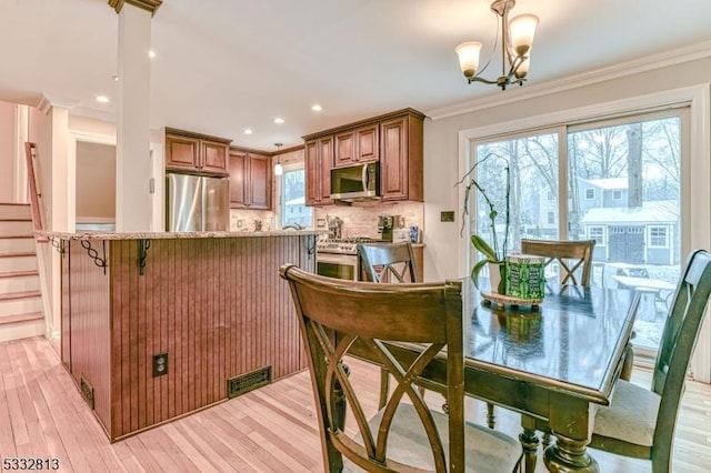 kitchen with appliances with stainless steel finishes, a notable chandelier, crown molding, and tasteful backsplash