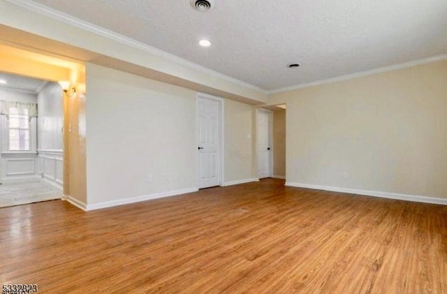 unfurnished room with light hardwood / wood-style flooring, a textured ceiling, and ornamental molding