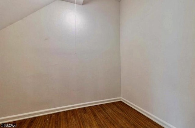 spare room with dark hardwood / wood-style floors and lofted ceiling