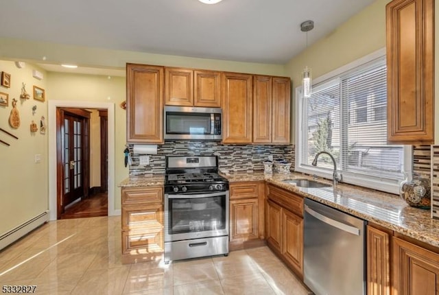 kitchen with a baseboard heating unit, pendant lighting, sink, stainless steel appliances, and light stone counters