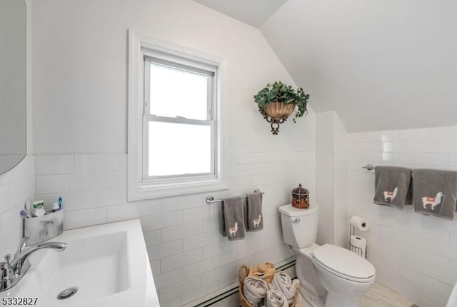 bathroom featuring baseboard heating, sink, tile walls, toilet, and vaulted ceiling