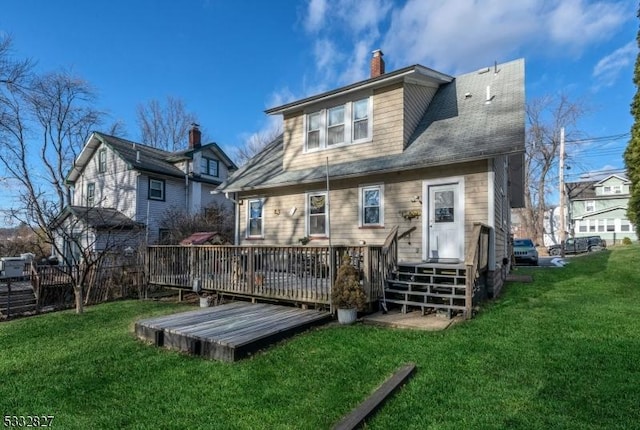 rear view of house featuring a wooden deck and a yard