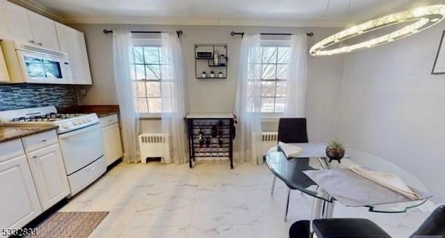 kitchen featuring backsplash, radiator, white cabinetry, and white appliances