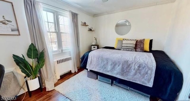 bedroom featuring dark hardwood / wood-style flooring, radiator heating unit, and crown molding