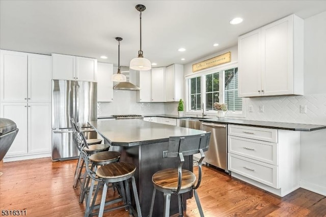 kitchen with stainless steel appliances, hanging light fixtures, dark wood-type flooring, a kitchen island, and white cabinetry