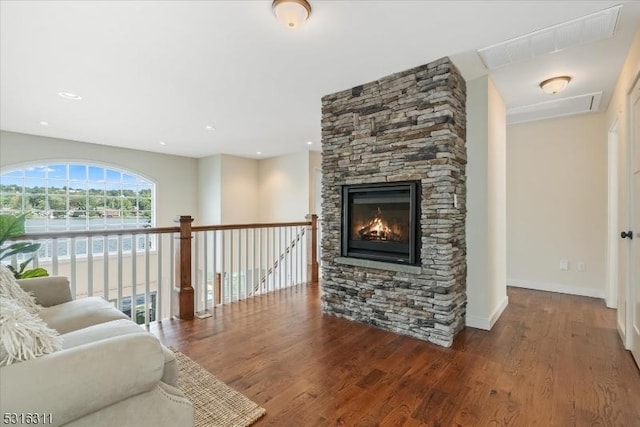 living room with hardwood / wood-style floors and a stone fireplace