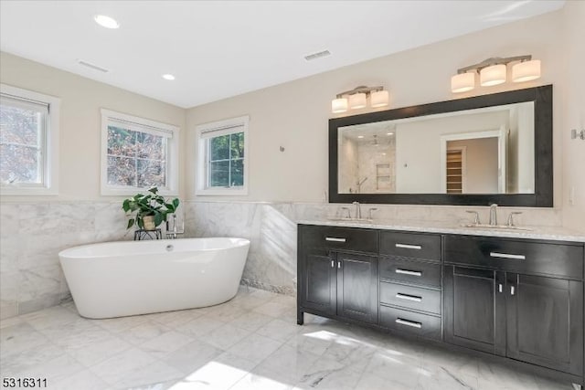 bathroom with tile walls, a tub, and vanity