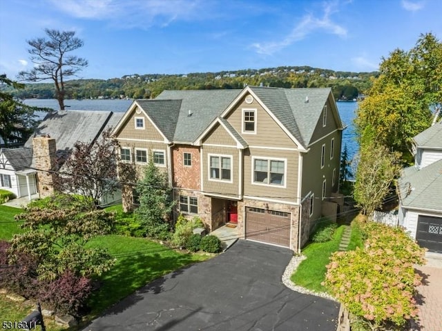 view of front facade featuring a front lawn, a garage, and a water view