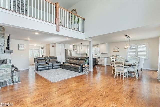 living room featuring light hardwood / wood-style floors, a towering ceiling, and plenty of natural light