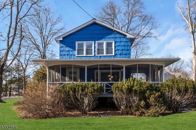 rear view of property featuring a yard and a sunroom